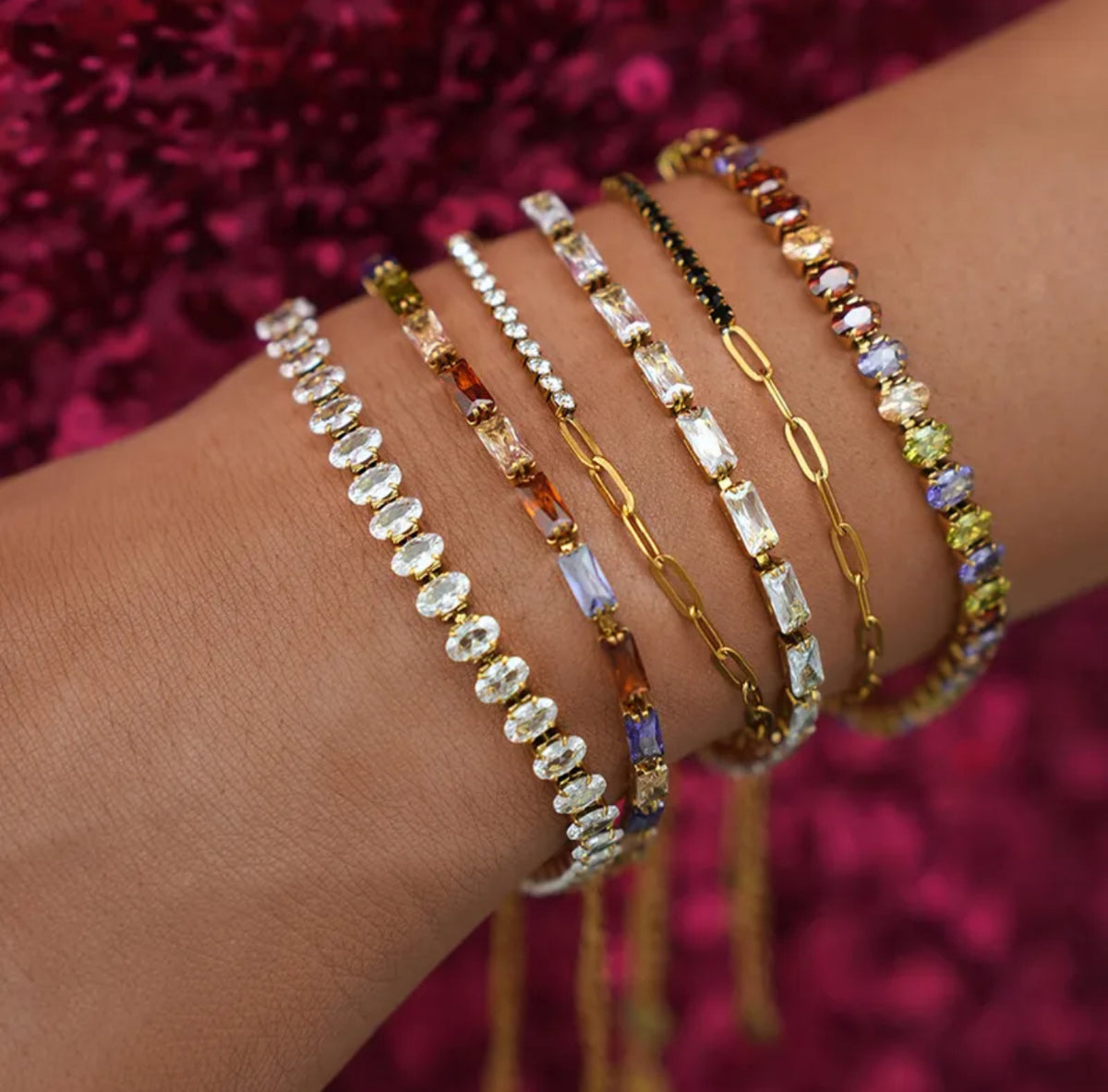 Close-up of a wrist wearing multiple beaded bracelets against a pink textured background