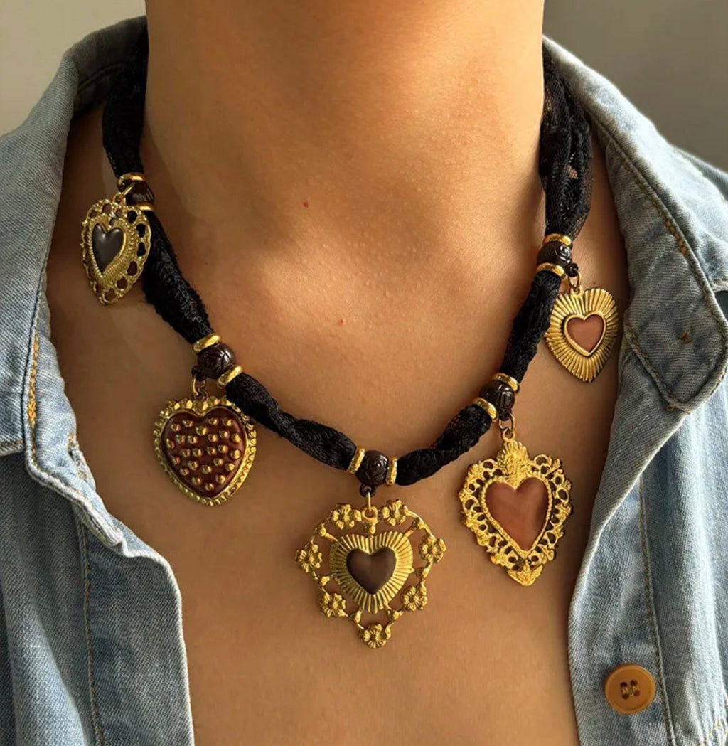 Necklace with heart-shaped pendants on a person wearing a denim shirt.