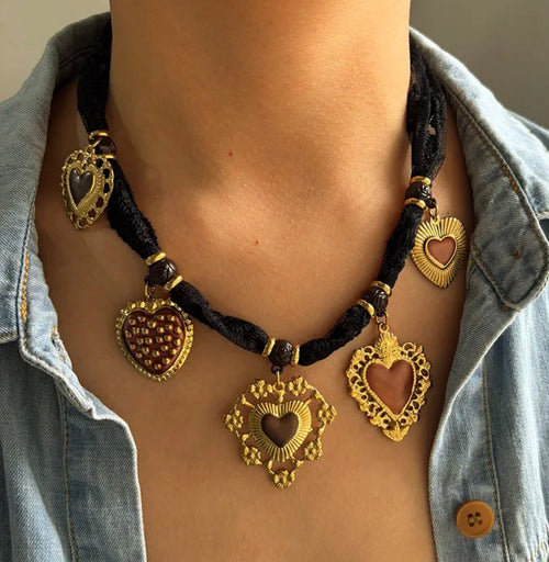 Necklace with heart-shaped pendants on a person wearing a denim shirt.